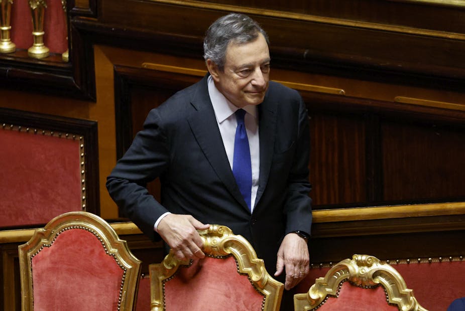Mario Draghi holds onto the back of a chair in the Italian senate