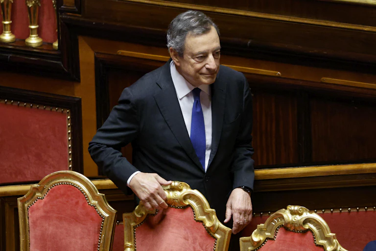 Mario Draghi holds onto the back of a chair in the Italian senate