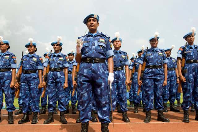 A row of female police officers in blue camp line up.