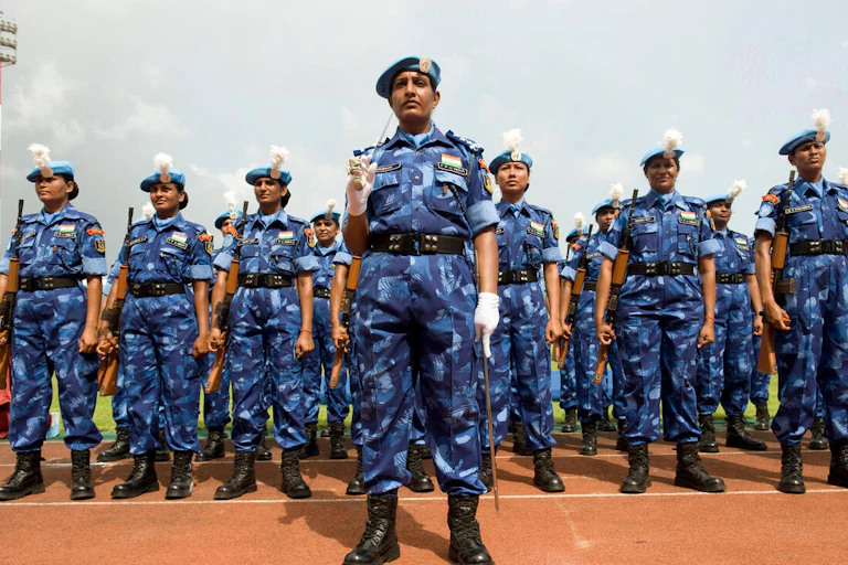 A row of female police officers in blue camp line up.