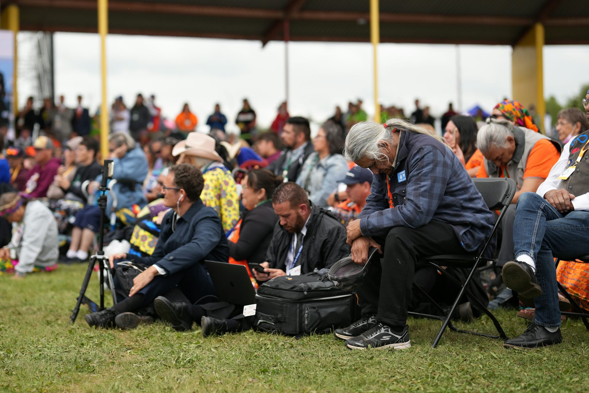 Des gens sont assis, têtes baissées.