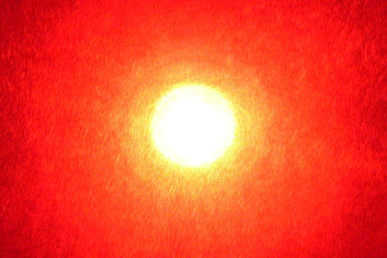 a bright ball of white light surrounded by a halo of orange wider halo of red