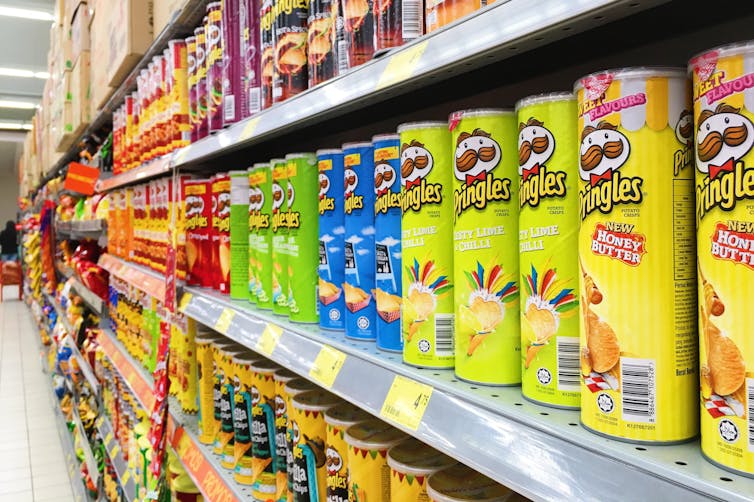 A row of Pringles cans on the shelf of a grocery store