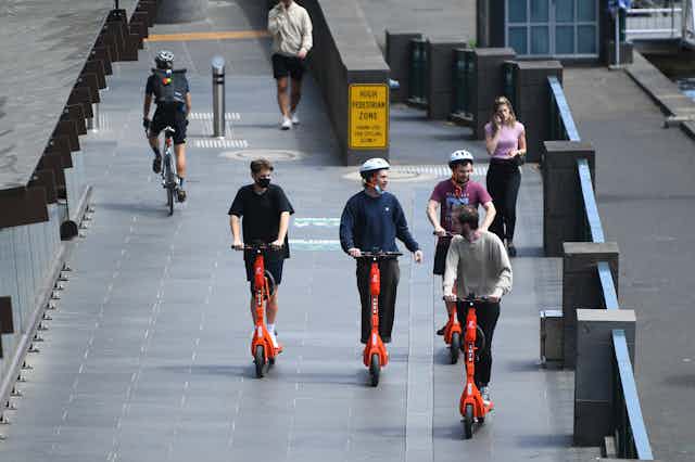 People riding orange e-scooters in Melbourne