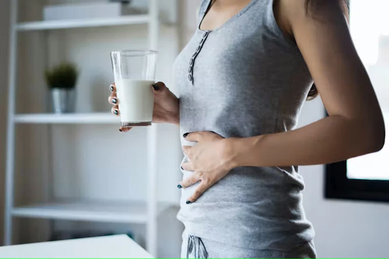 Wanita memegangi perutnya dan memegang segelas susu