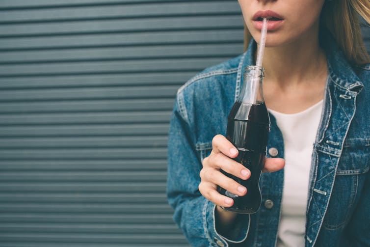 girls with soda bottle drinks through straw