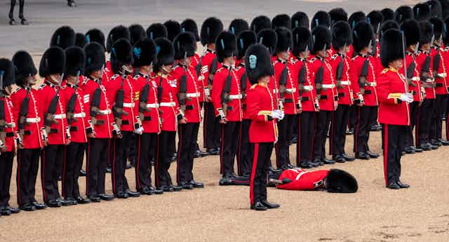 A row of Coldstream Guards with one who has fainted.