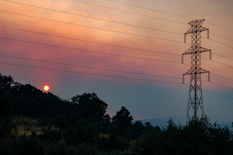 A sunset with a hill and an electric pylon in the foreground.