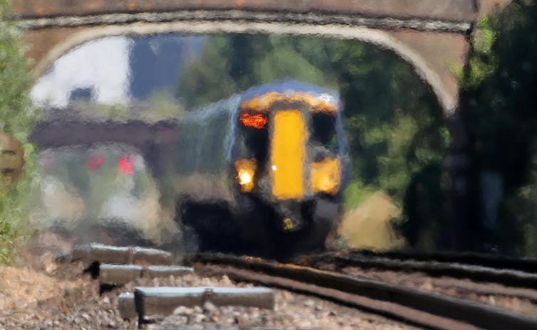 A train passing under a bridge in the distance through heat haze.