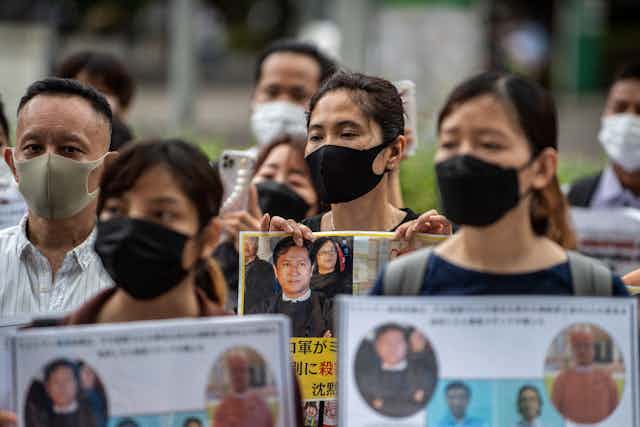 Activists including Myanmar citizens  protest in Tokyo - they are wearing face masks and holding photos of the men killed.