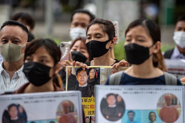 Activists including Myanmar citizens protest in Tokyo - they are wearing face masks and holding photos of the men killed.