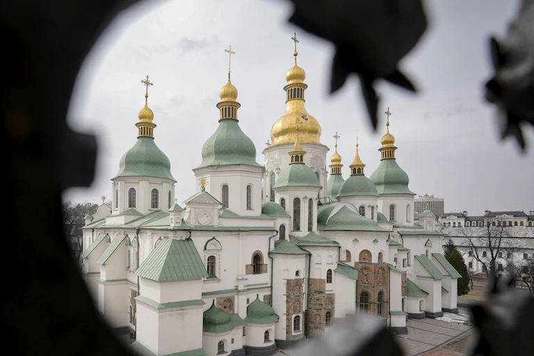 An imposing monument with green and golden domes, seen against a blue skyline.