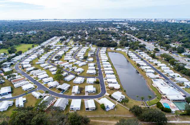 Manufactured homes line curving streets around a lake.
