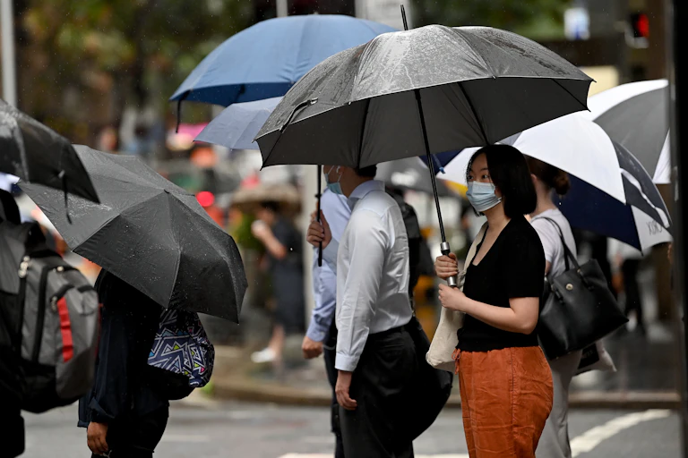 people in street with masks and umbrellas
