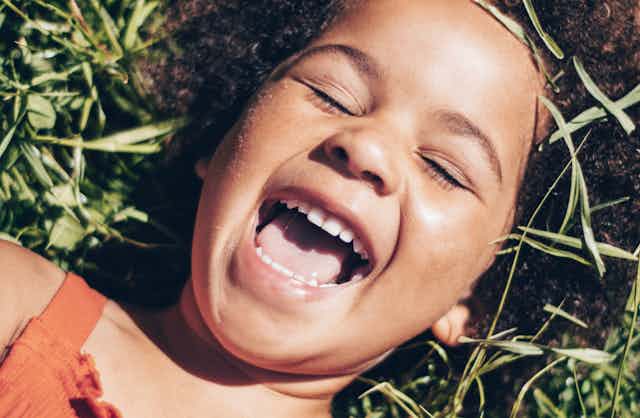 child on grass laughing and showing teeth