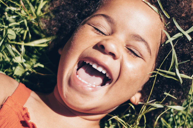 child on grass laughing and showing teeth