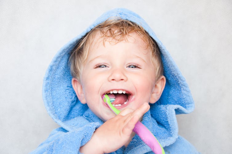 child in hood, brushing teeth