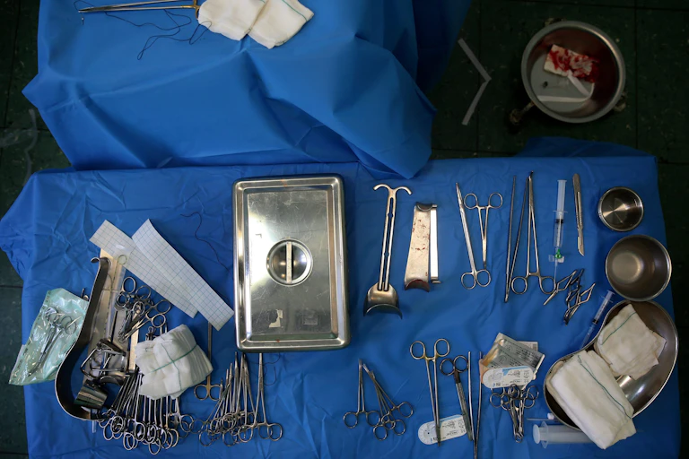 Two tables draped in blue cloth with surgical implements on them