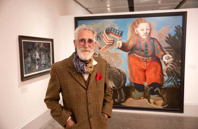 Scottish artist John Byrne standing in front of one of his paintings.