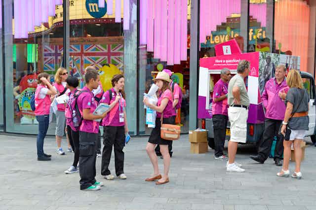 People in purple t-shirts stand in front of a colourful building.