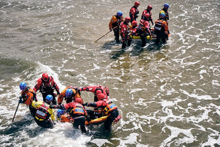 People in life jackets on inflatables in the waves.