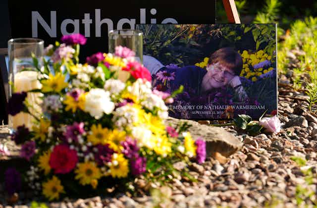 A bouquet of flowers its in front of a memorial sign of smiling woman. 