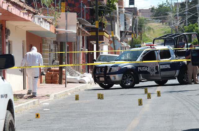 A police officer in forensic clothing examines the scene of a shootring on a street in Apaseo El Grande in Mexico