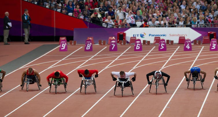 Wheelchair racers on an parathletics track.