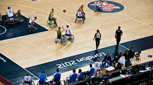 Wheelchair basketballers on a court with a ball.