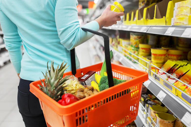Shopper browsing a shelf in a grocery store with a basket on one arm