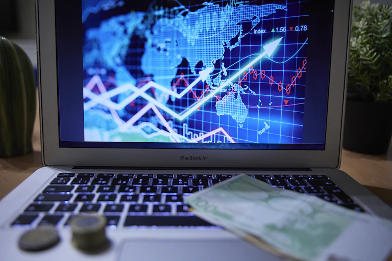 A chart on a laptop computer with banknotes and coins