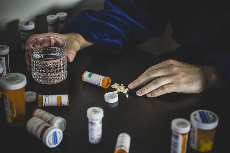 Hands surrounded by pill bottles on a table