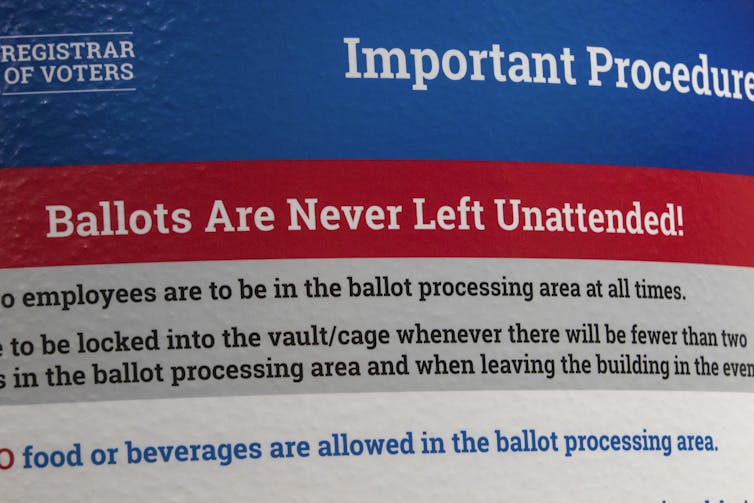 A red, white and bue sign that says 'Important Procedures' at the top and says 'Ballots Are Never Left Unattended!' lower down.