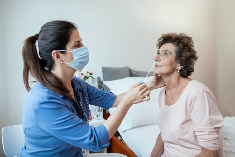 Aged care worker takes a nasal swab from a resident