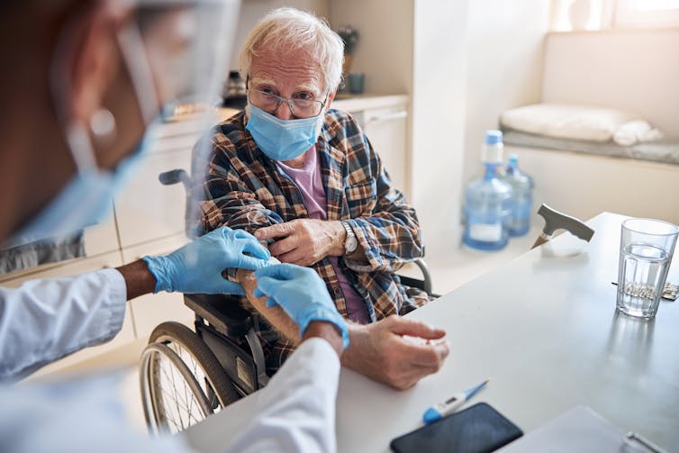 Nurse puts bandaid on resident's arm