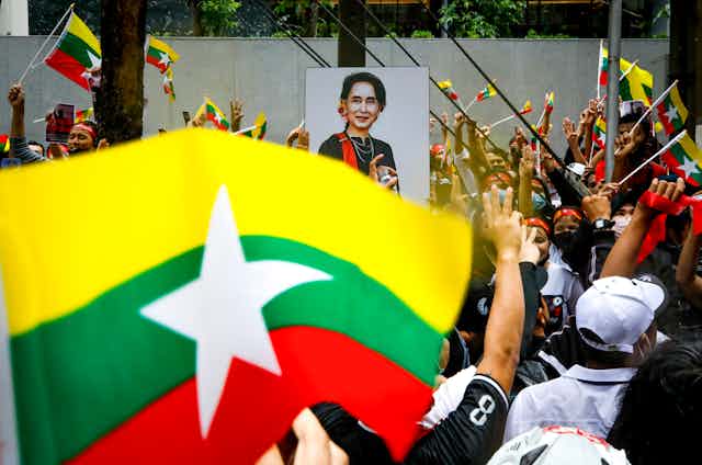 A crowd of protesters waving Myanmar flags and banners with the jailed leader Aung San Suu Kyi outside the Myanmar embassy in Bangkok, July 2022.