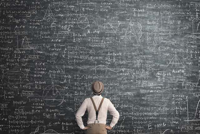 Man viewing a blackboard filled with equations.