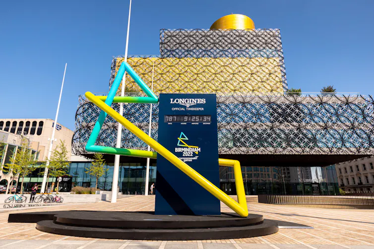 A clock in front of a library under a blue sky.