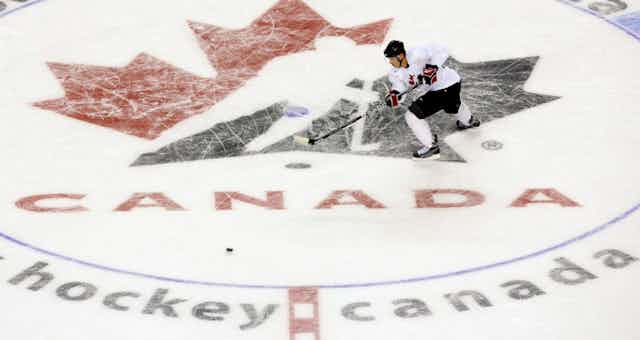 A hockey player skates across a Hockey Canada logo 