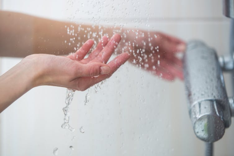 A hand testing the shower water while adjusting the tap.
