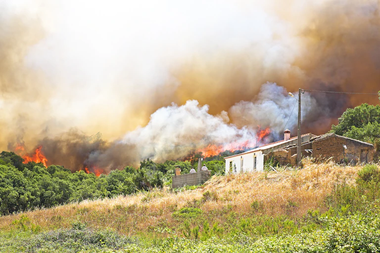Una casa en un paisaje con un fuego que se acerca