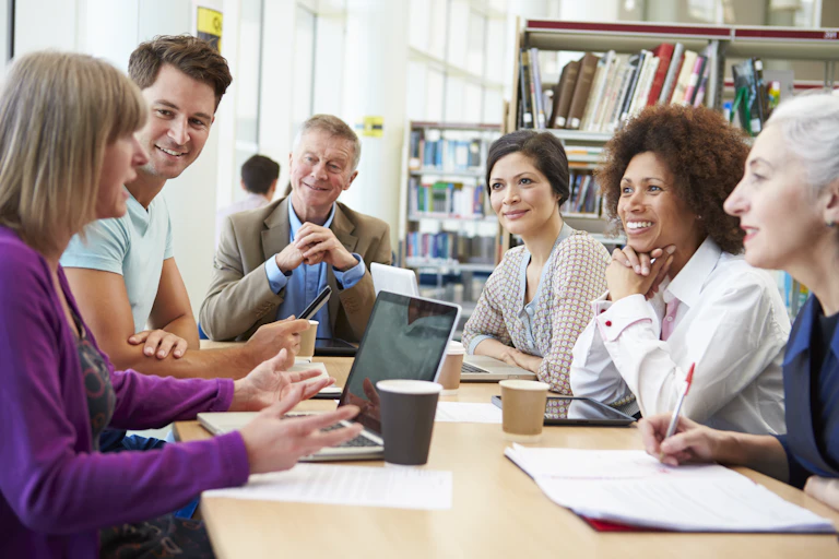 A group of students, some older and some younger, at a table.