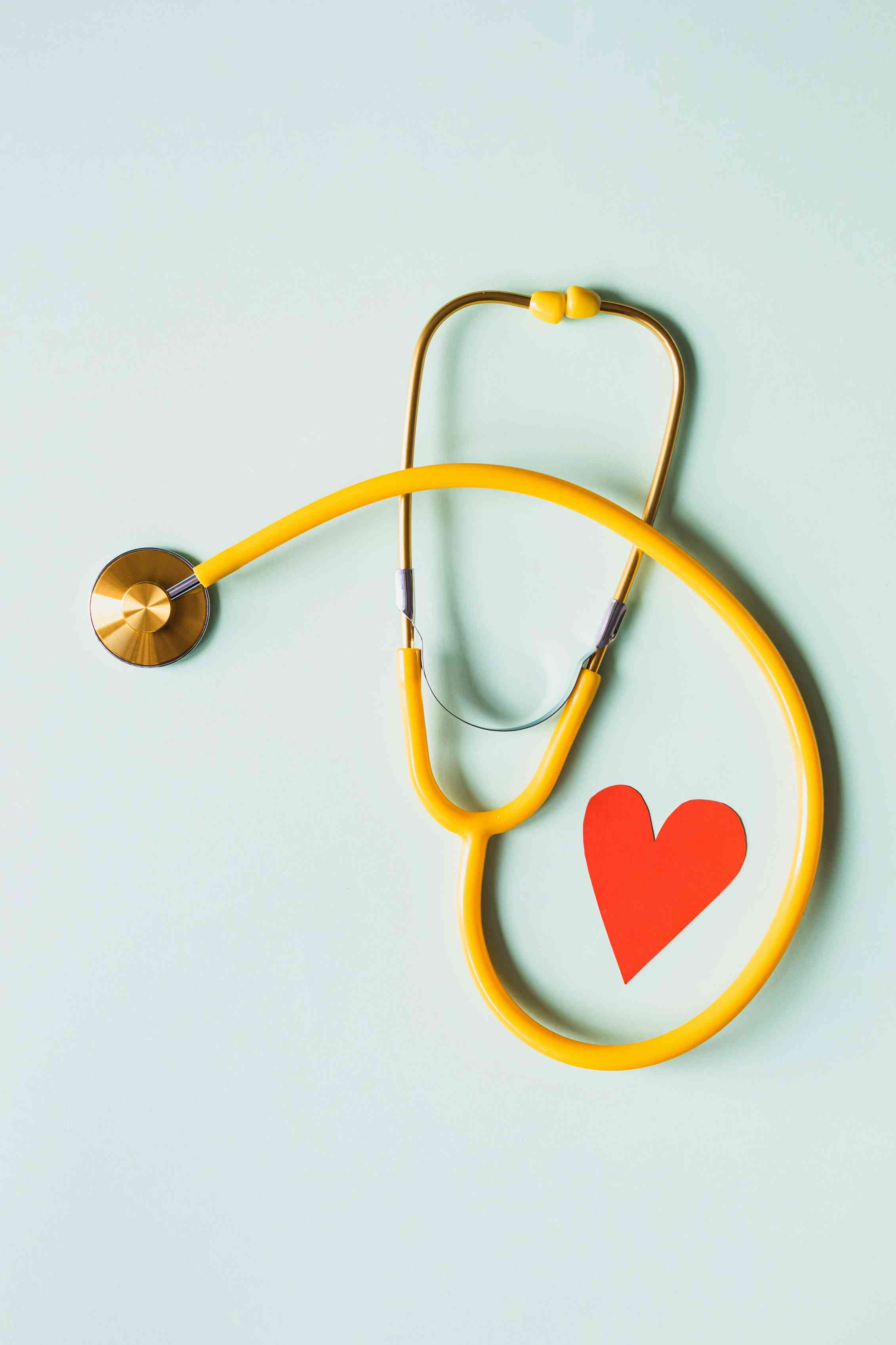 Stetoscopio medico con cuore di carta rosso su superficie bianca