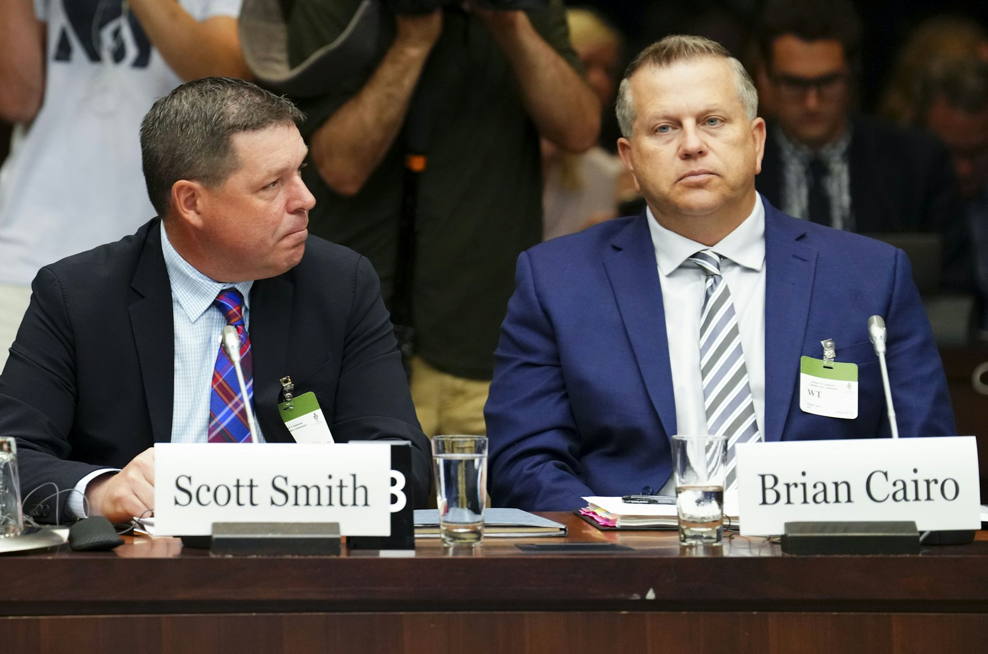 Two men are sitting at a table with name tags in front of them.