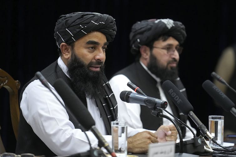 A bearded man speaks into a microphone.