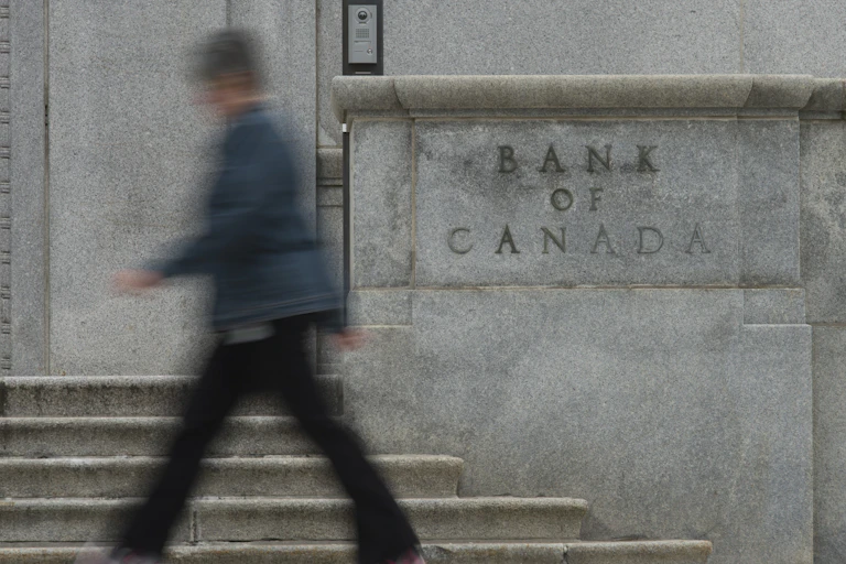 A blurry figure walks past the Bank of Canada building sign in Ottawa