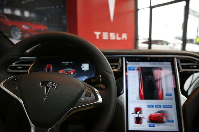 The inside of a Tesla vehicle parked in a Tesla showroom
