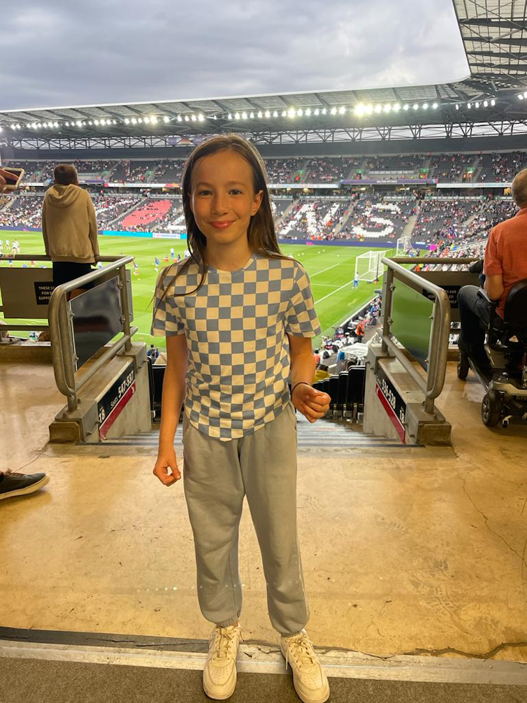 A smiling young girl in the grandstand at the EUros 2022 semi-final between France and Germany at Stadium MK in Milton Keynes.