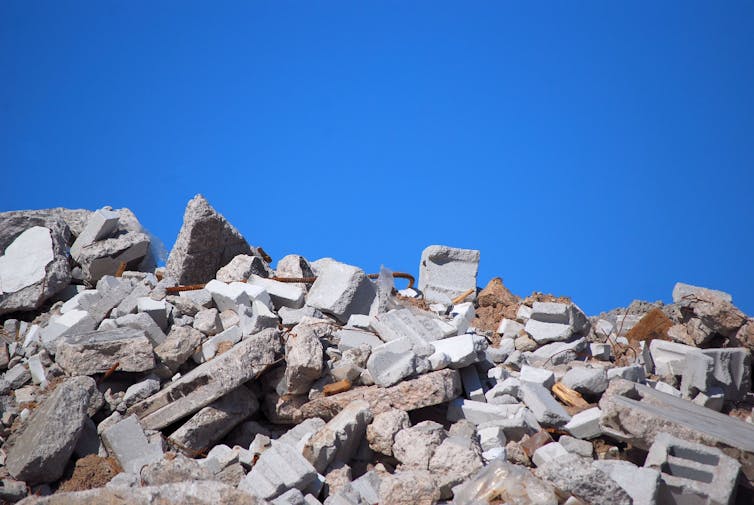 Concrete rubble of a demolished building against a blue sky.