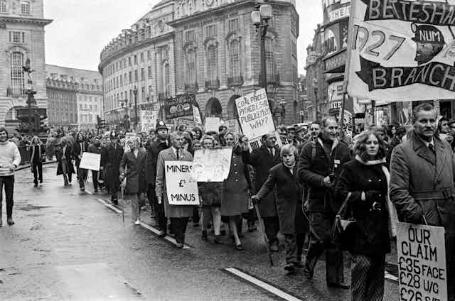 Long line of people with signs marching through Piccadilly Circus, London, 1972